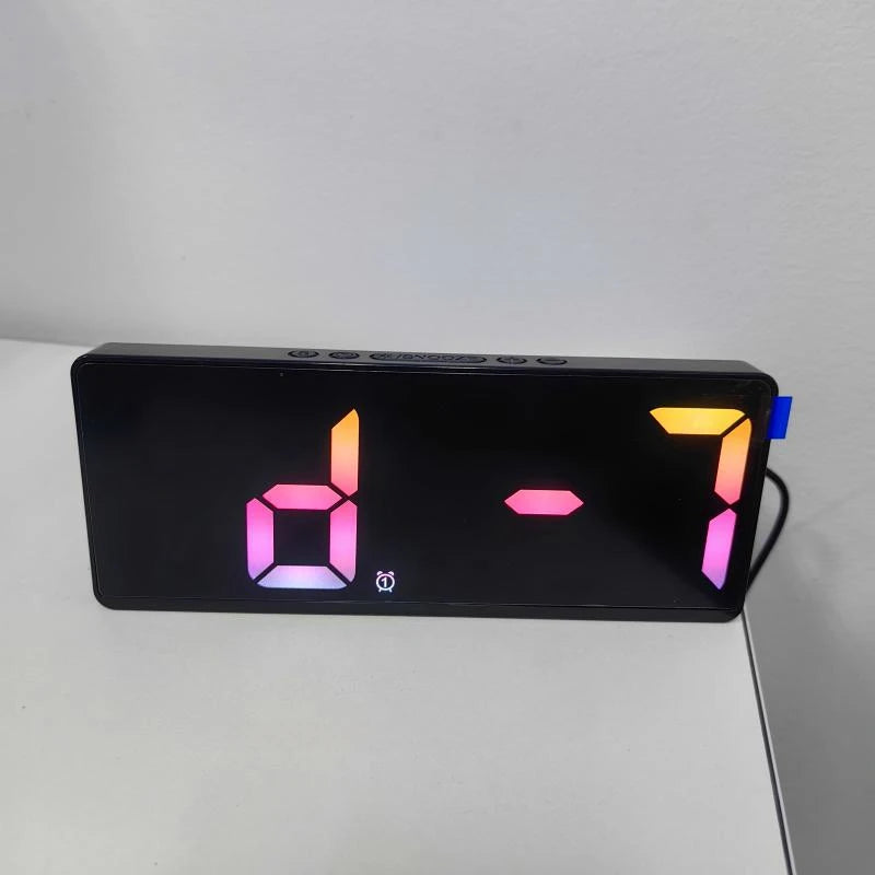 A black digital alarm clock displaying the time 07:00 with pink and orange segmented digits.