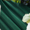 Deep emerald green chiffon fabric draped elegantly with dark berries and light floral accents.