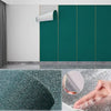 Gros plan d'une main touchant un autocollant mural vert texturé sur une surface.