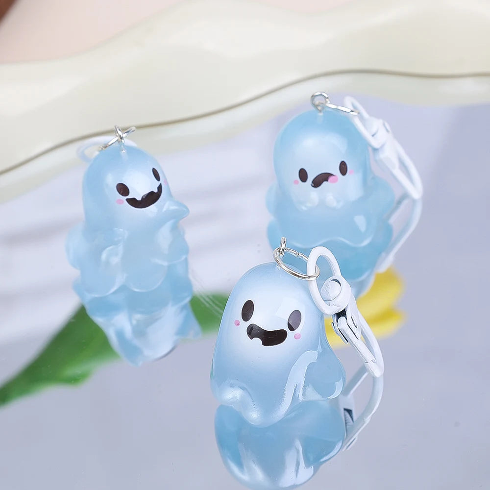 A translucent light blue ghost keychain with a smiling face and a clear plastic charm on a white background.