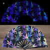 A folding fan featuring a dark background with vibrant UV fluorescent cannabis leaf patterns.