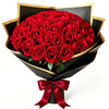 A bouquet of 50 deep red velvet artificial roses wrapped in black paper and tied with a satin ribbon.
