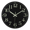 A black wall clock face with white numbers and hands, featuring a glow-in-the-dark design.