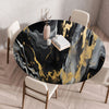 A round table set for dining featuring a black and gold marble print tablecloth on a wooden table.