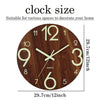 Reloj de pared redondo de madera con esfera marrón oscura y números y manecillas verde claro, mostrando la hora.