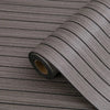 Roll of self-adhesive 3D wood grain wall panels showing a dark gray textured surface.