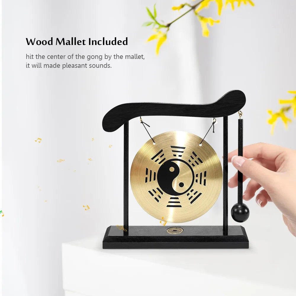 A round brass gong suspended in a black frame with a wooden mallet, demonstrating a Zen sound instrument.