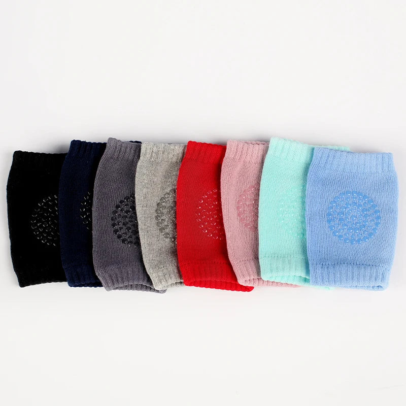 A row of colorful knitted knee pads for crawling infants in various shades of purple, blue, pink, and red.