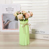 A light green plastic vase holds a bouquet of pink roses on a wooden surface.