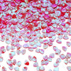 A close-up of pink and red sea shell PVC sequins scattered across a white background for nail art and craft decoration.
