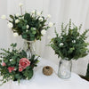 A floral arrangement featuring green eucalyptus leaves and white flowers in glass vases.