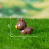 A small brown animal figurine with yellow accents placed on green grass.