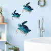 A teal and blue iron wall art sculpture of a sea turtle hanging on a light blue wall above a sink.
