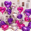A collection of iridescent and metallic foil heart balloons in various shades of purple and pink displayed on a white shelf.