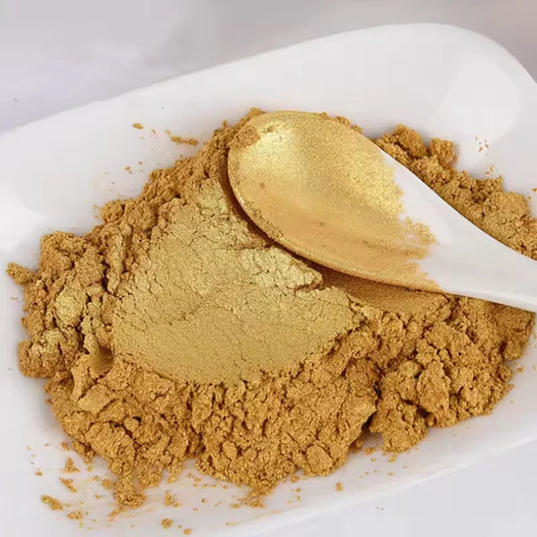 A spoonful of gold glitter dust is shown on a white plate.