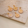 A set of gold-toned religious pendants featuring St. Benedict imagery, displayed on a light beige surface.