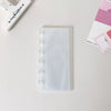 A clear vertical transparent photocards holder with white binding and a clip is shown on a white surface.