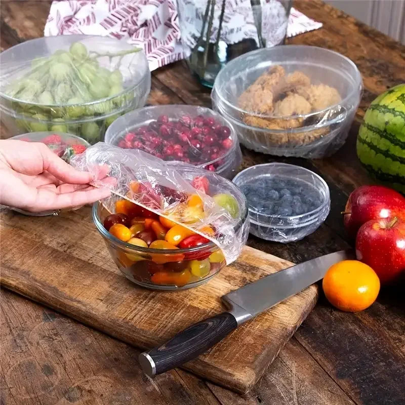 Reusable food storage bags with decorative bows filled with colorful fruits and nuts on a wooden board