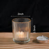 A clear glass votive candle holder with vertical ribbing, measuring 2 inches high.