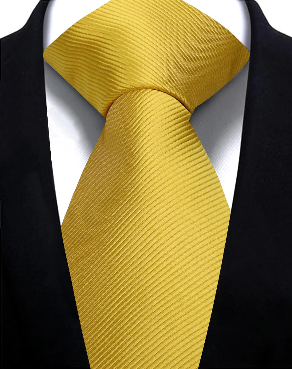 A close-up of a solid gold yellow silk necktie tied in a knot against a black suit jacket.