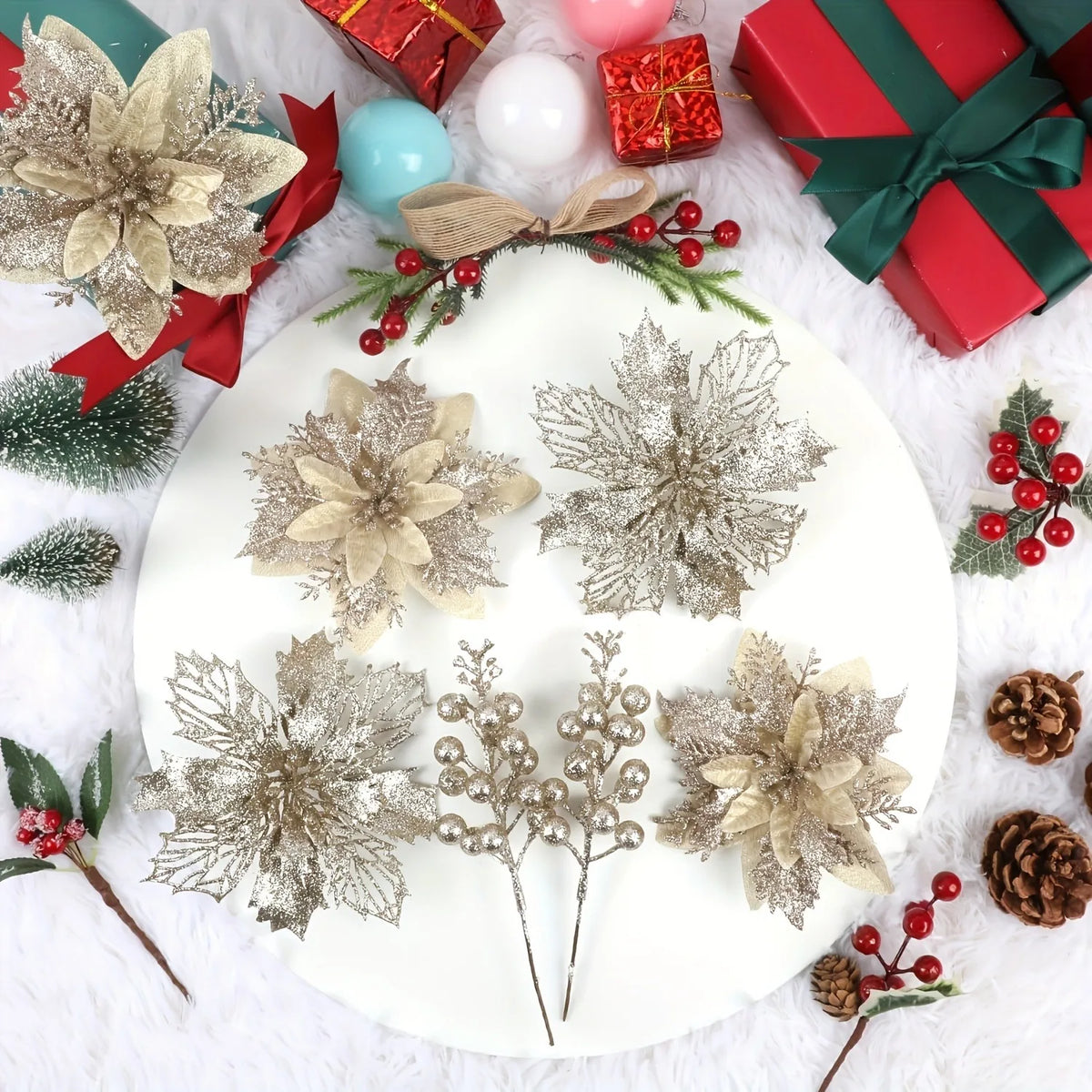 A white plate displays artificial silver and gold floral arrangements and red wrapped gifts on a white fluffy surface.