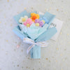 A bouquet of handmade crochet sunflower mini flowers in pastel colors, wrapped in light blue paper.