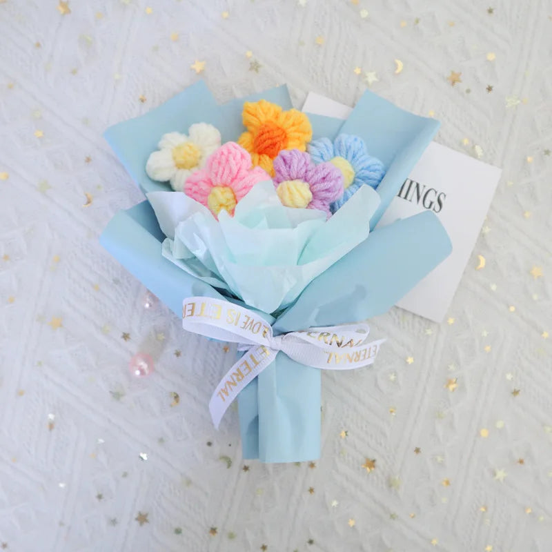 A bouquet of handmade crochet sunflower mini flowers in pastel colors, wrapped in light blue paper.