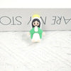 A small resin statue of the Virgin Mary with a yellow halo and green garment displayed on a white textured surface.