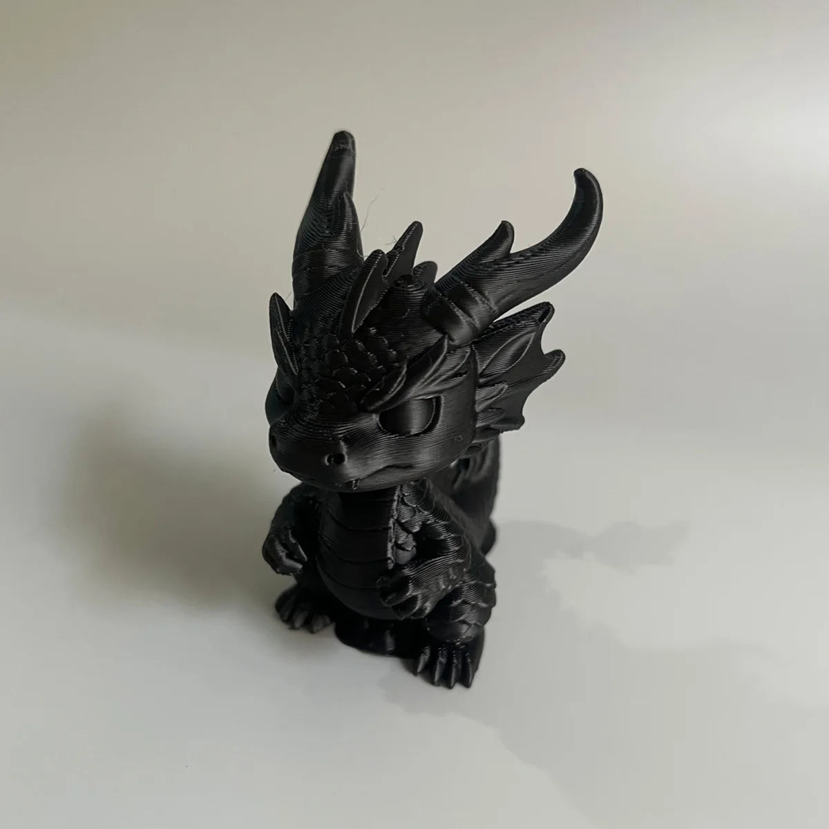 Figurine de dragon miniature noir pour bureau, avec des cornes pointues et une texture détaillée.