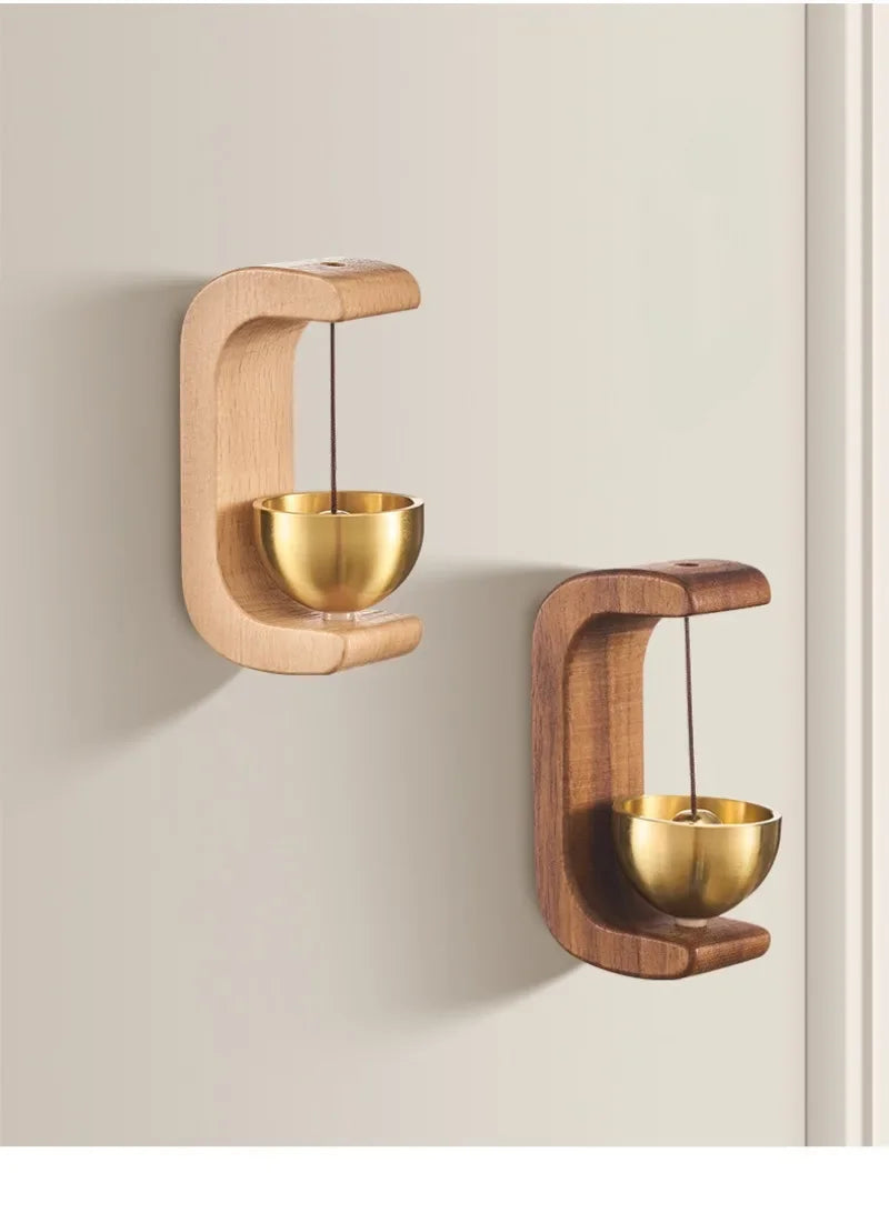 A magnetic wooden doorbell with a brass bell mounted on a wall.