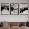 Three framed black and white canvas prints depicting hands reaching toward each other
