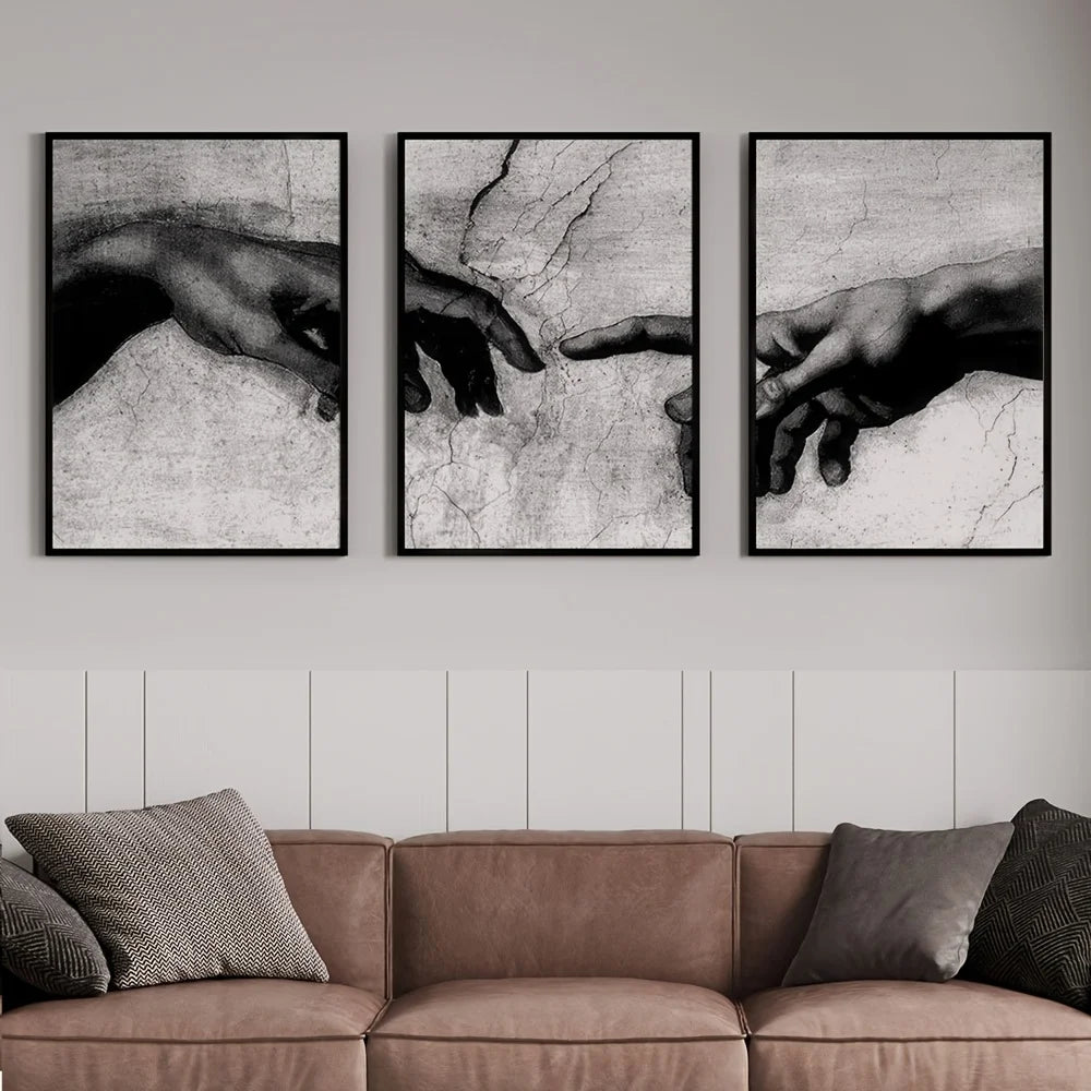 Three framed black and white canvas prints depicting hands reaching toward each other