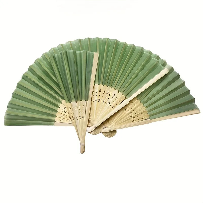 A set of light green and natural wood folding fans displayed open, showing the pleated fan blades.