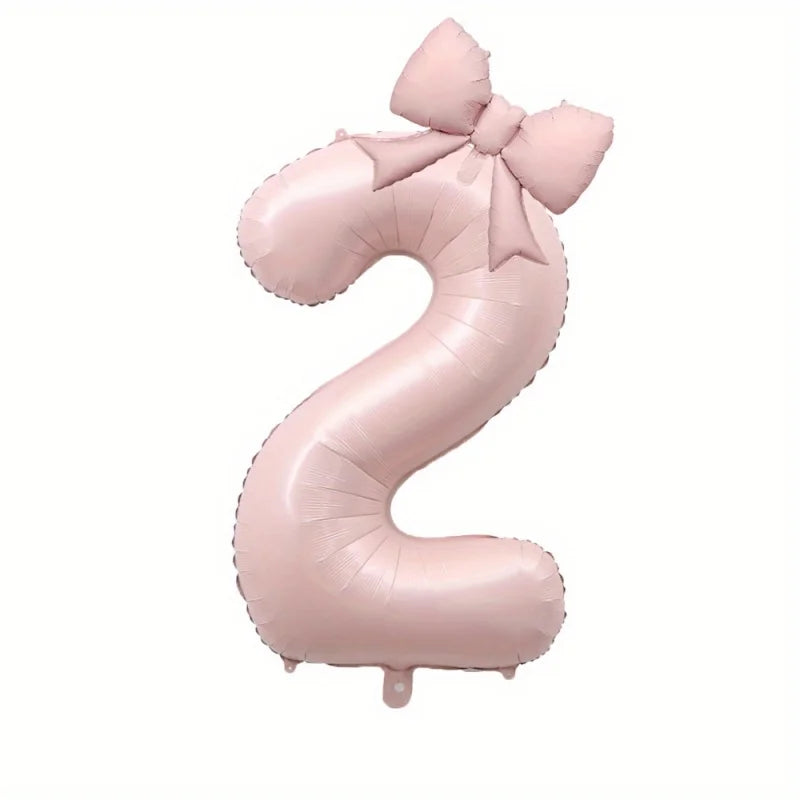 A large pink foil number balloon shaped like the number 2 with a bow.