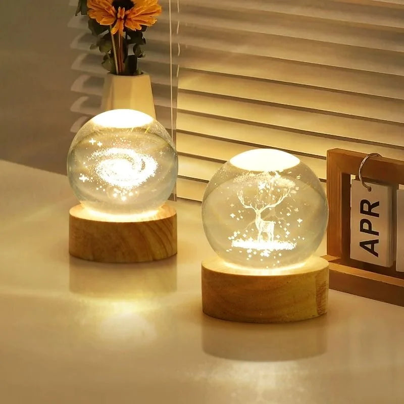 A glowing crystal ball night light with a white deer silhouette on a wooden base.