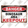 A vintage metal warning sign with red and white text that reads DANGER DINOSAUR AREA KEEPOUT