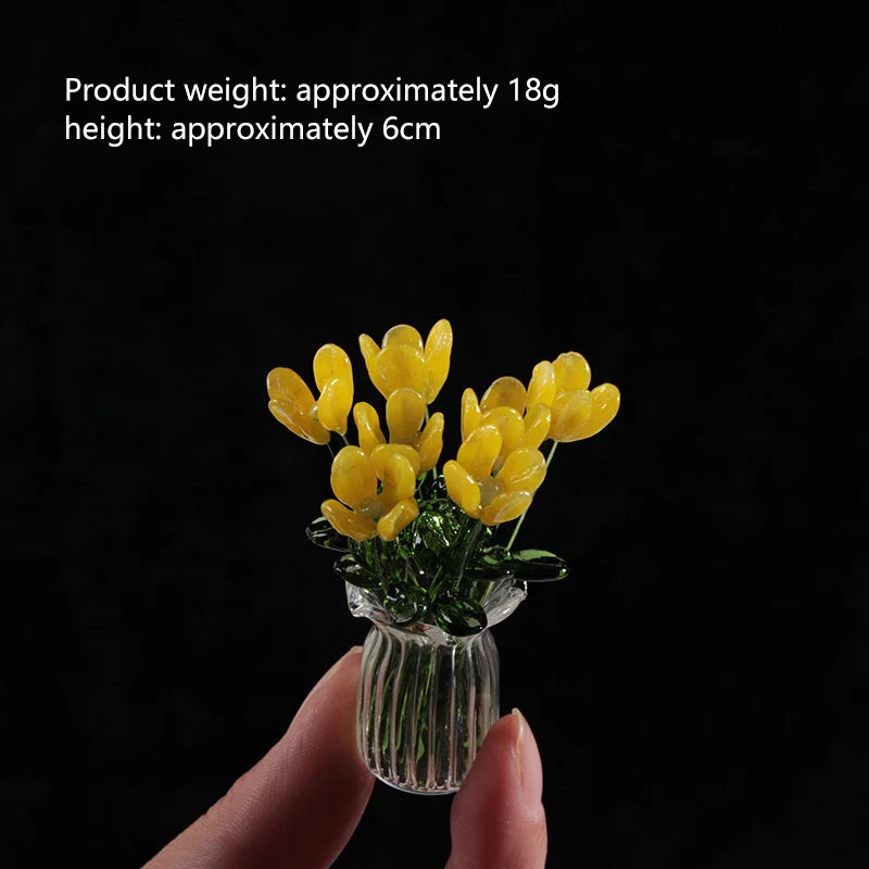A hand holds a small glass vase filled with yellow handmade flowers for home decor.