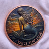 A round copper challenge coin featuring a mermaid design with flowing hair and scales against a sunset background.