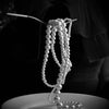 A delicate strand of white pearls rests on a white plate against a dark background.