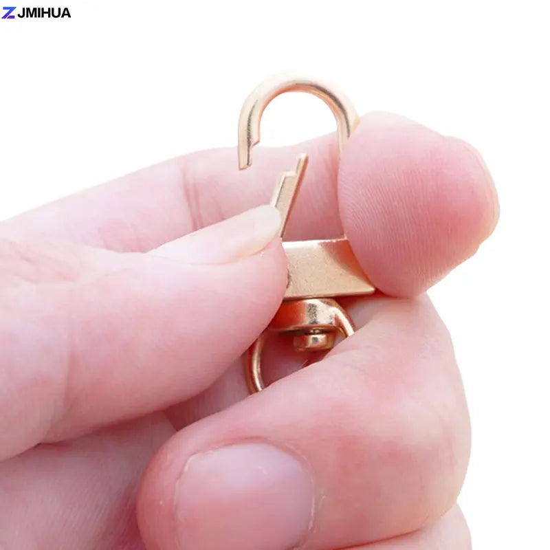 A hand holds a gold-colored lobster clasp hook used for jewelry making or DIY crafts.