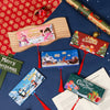 A festive cash gift box with 10 slots and various holiday-themed cards is displayed on a dark blue background.