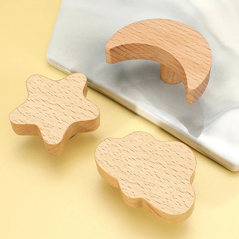Two wooden animal hooks, one star-shaped and one cloud-shaped, resting on a white surface.