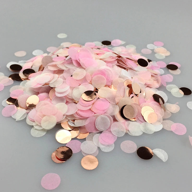 A pile of multicolor paper confetti consisting of pink, gold, and white circular pieces.