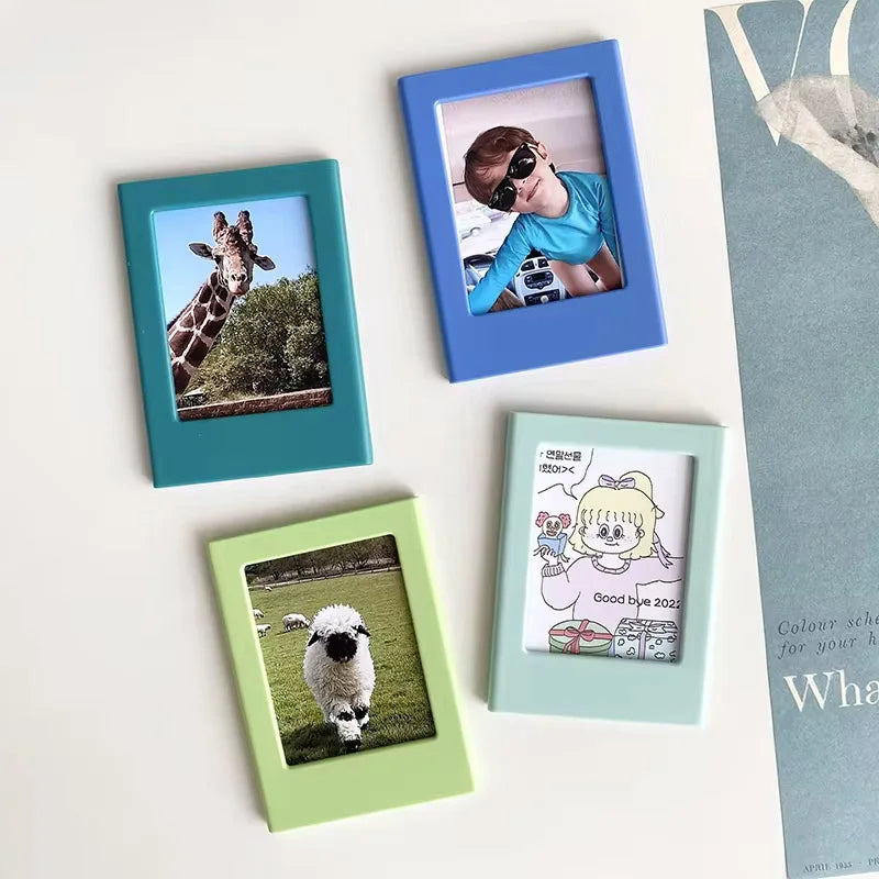 Four magnetic photo frames in shades of blue, teal, and green displaying images of a giraffe and a person.