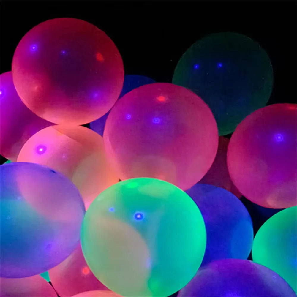 A close-up of various neon glow latex balloons in shades of pink, green, and purple against a dark background.
