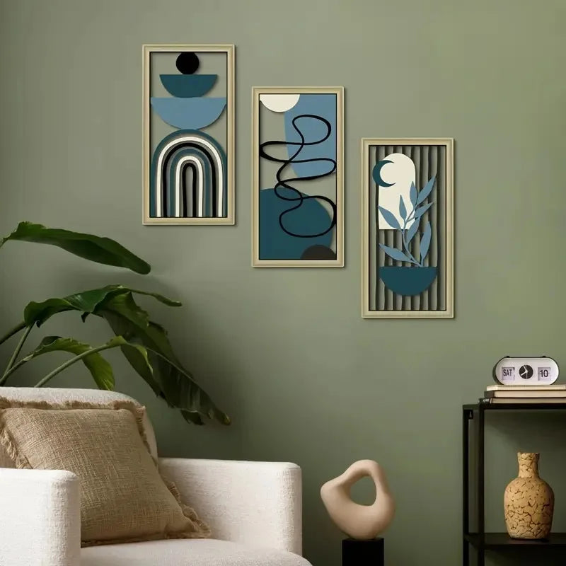 Drei gerahmte Holzdekorationsobjekte mit abstrakten blauen und grauen geometrischen Designs an einer gedämpft grün gestrichen