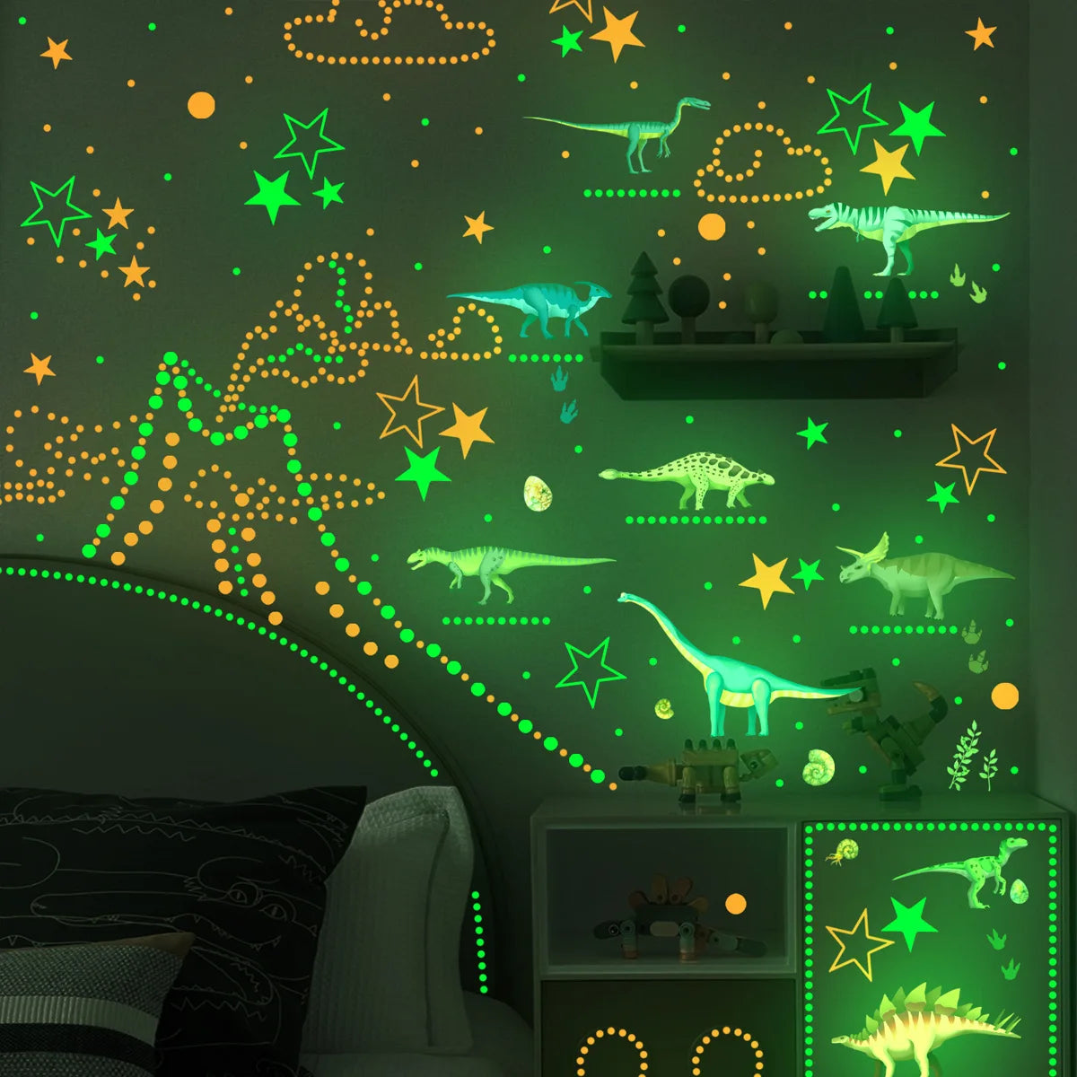 A green wall decorated with glow-in-the-dark dinosaur stickers and stars for a child's room.