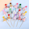 A set of mini birthday cake toppers featuring various colored and patterned conical shapes on wooden sticks.