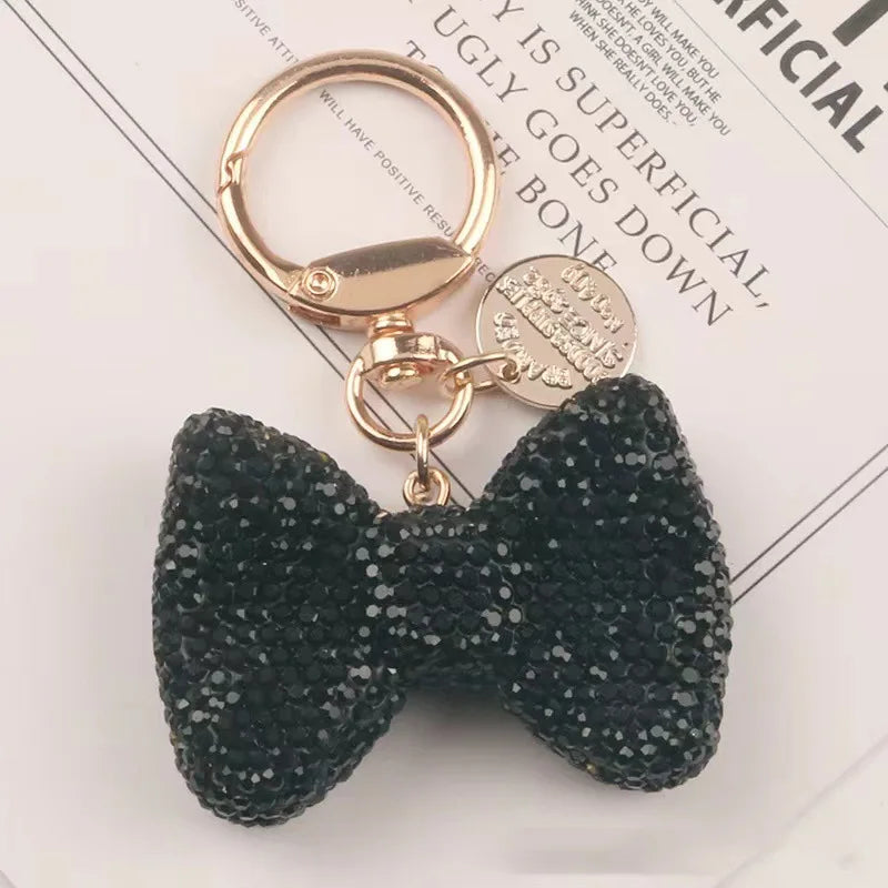 A black sparkling rhinestone bow keychain with a gold-toned ring and clasp.