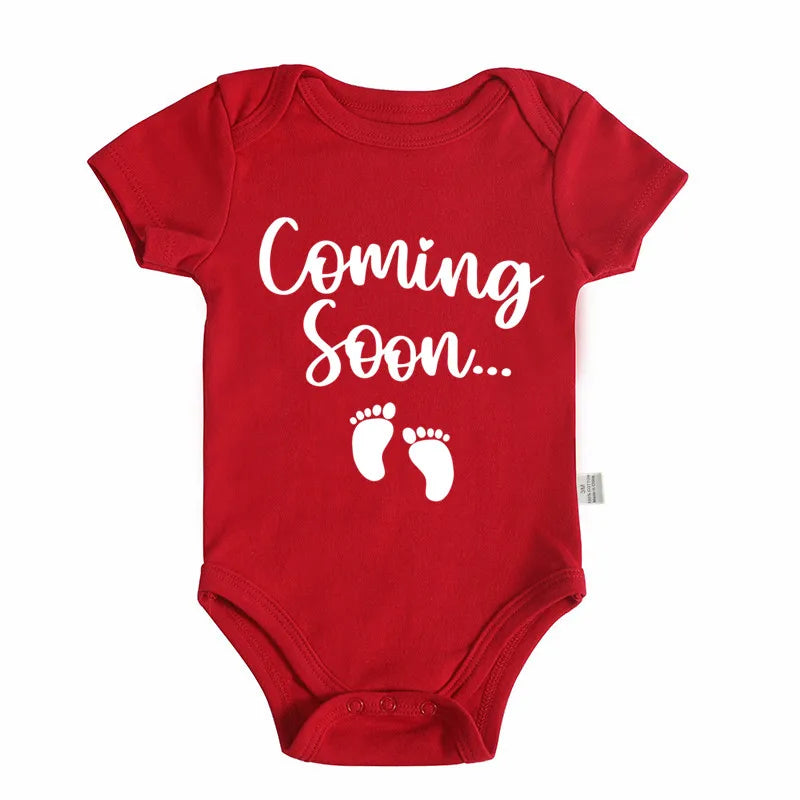 A red baby bodysuit with white text that reads Coming Soon